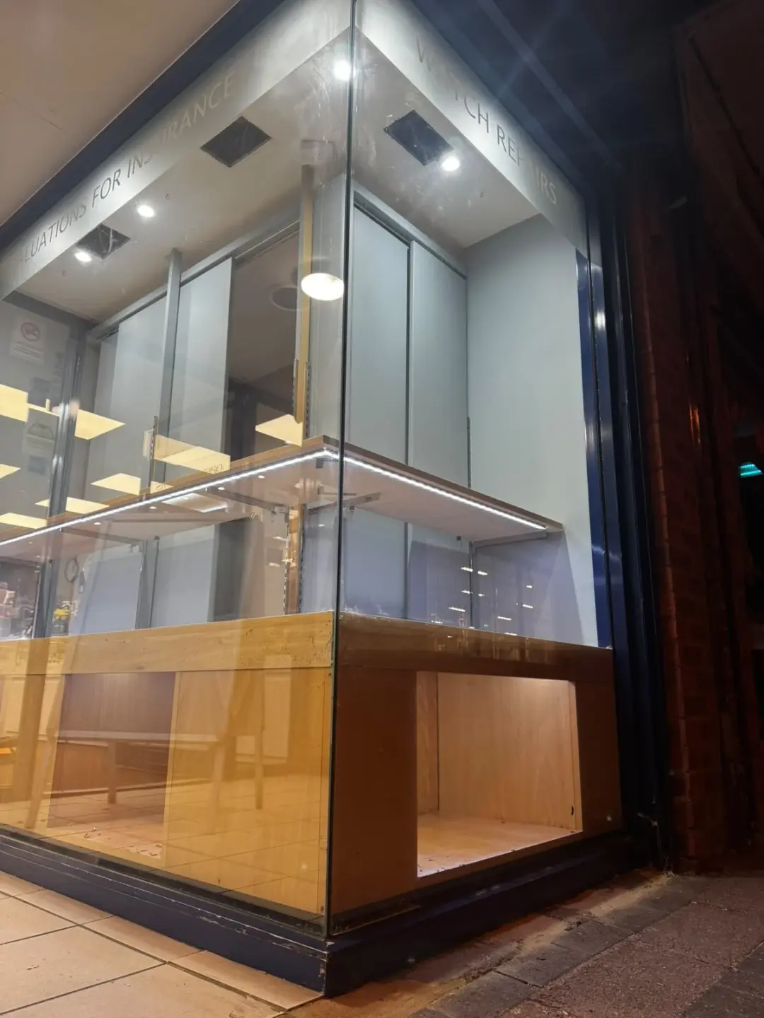 Lit shop display cabinets behind a glass shopfront at night